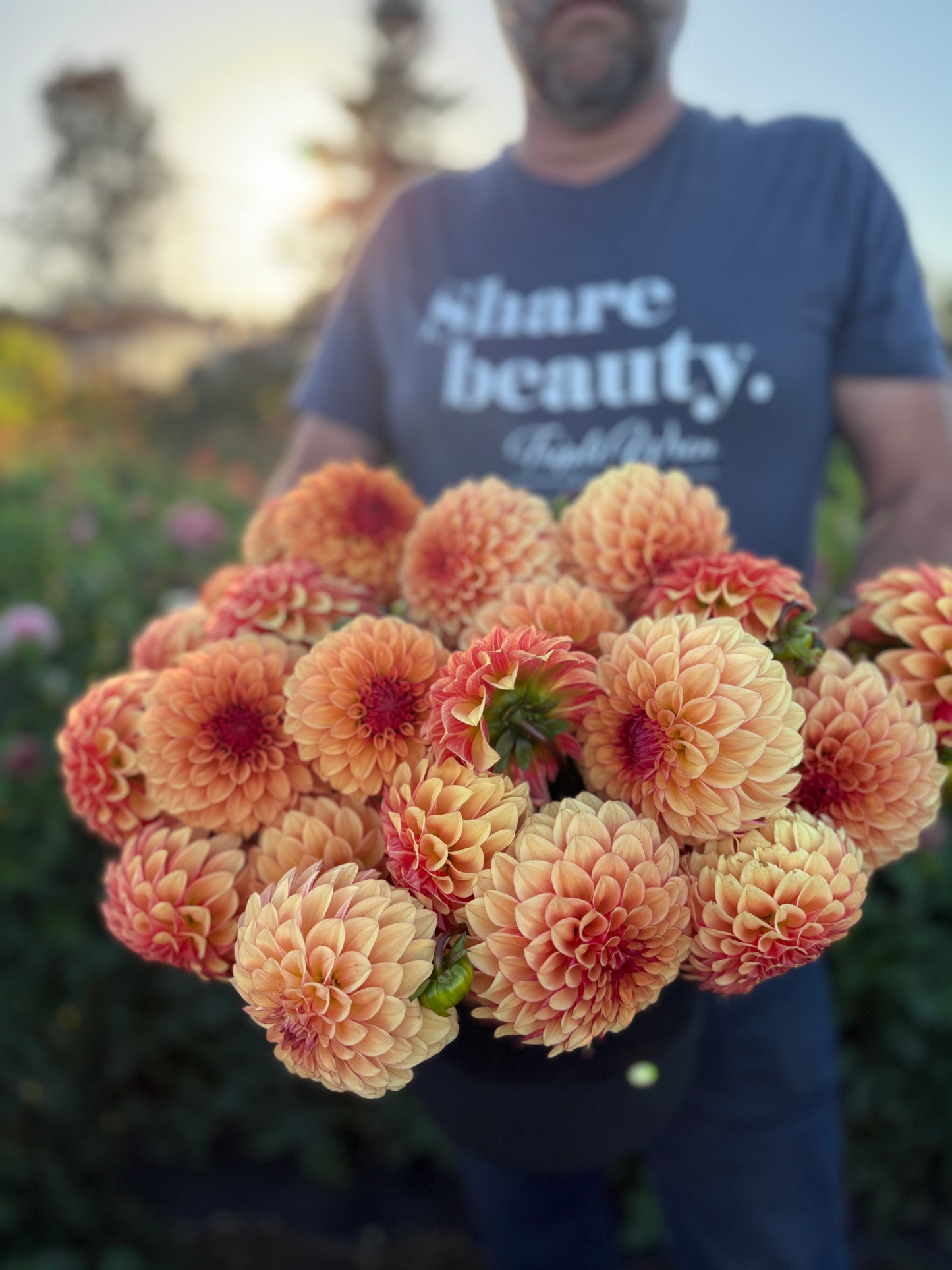 Person holding a bouquet of flowers with 'Share beauty' t-shirt in the background
